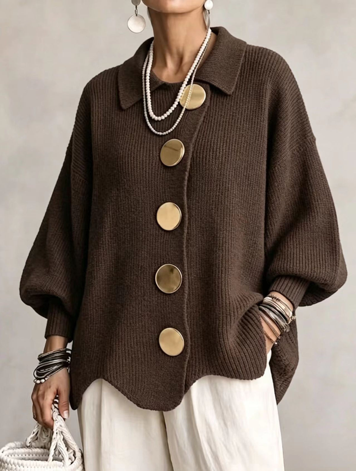 Loose-fitting solid color collared knit sweater with metal buttons and an irregular hem